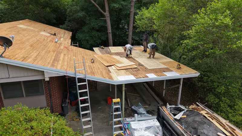 Roofers fitting new plywood over old boards on a carport roof, Wilmington, NC